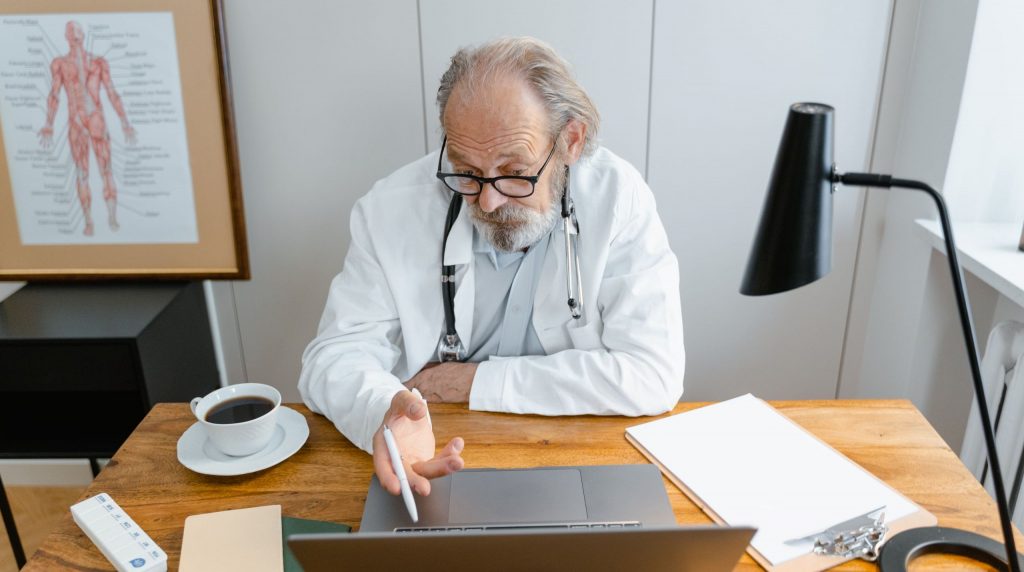 médecin travaillant sur un ordinateur portable à son bureau, tasse de café à portée de main